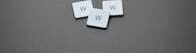 Three white letter tiles with 'W' on a gray surface, minimalist design